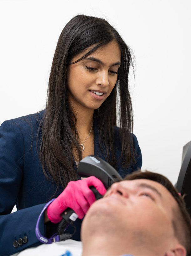Dr. Leena Ramani in a blue suit jacket working with a patient